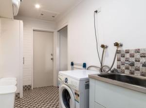 a laundry room with a washing machine and a sink at Spacious and Restful Holiday Home with Backyard in Weetangerra