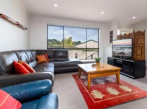 a living room with a leather couch and a table at Spacious and Restful Holiday Home with Backyard in Weetangerra
