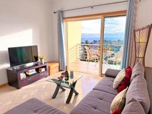 een woonkamer met een bank, een televisie en een balkon bij Luxury Apartment Ocean View by Be Cherish in Albufeira