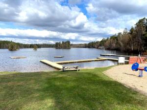 a large body of water with a dock in the grass at 5 person holiday home in Tving in Tving