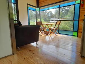 a living room with a table and chairs and windows at La casita del bosque en Muelle Delta Arias in Tigre +12 photos