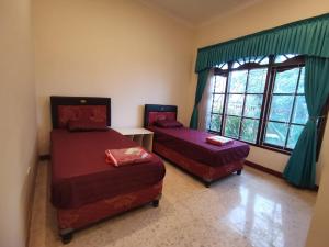 two beds in a room with a window at Villa Graha Permata 1 in Batu