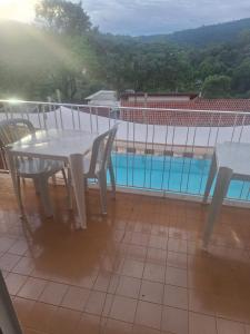 a white table and chairs on a balcony with a pool at Pousada Essenza lindoía in Águas de Lindóia