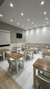a classroom with tables and chairs and a projection screen at Hotel Life Ijui in Ijuí