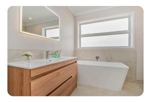 a bathroom with a sink and a tub and a mirror at Sand Castle in Whitianga