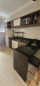 a kitchen with a black counter top and a refrigerator at Loft proximo a orla 01 in Presidente Epitácio