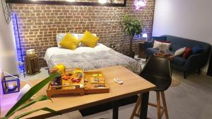 a room with a bed and a table with a table at GARY Suite - Studio Cosy, Spa et jardin privatif à 4 min de Cambrai in Awoingt