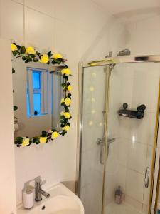 a bathroom with a sink and a shower with yellow flowers on the wall at Large Room Near City Centre in Belfast
