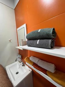 a bathroom with a sink and towels on a shelf at Apê da Lêda Loft - 400m da Praia do Forte in Cabo Frio +17 photos