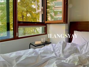a bed with a white comforter and two windows at 이랑스테이 ILANG Stay in Seoul