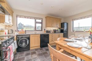 a kitchen with a washer and dryer and a table at Bryn-Weirglodd in Llanfihangel-y-pennant