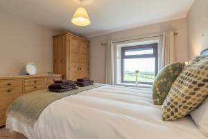 a bedroom with a large white bed with a window at Bryn-Weirglodd in Llanfihangel-y-pennant