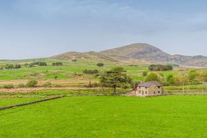 a house in a field with mountains in the background at Bryn-Weirglodd in Llanfihangel-y-pennant