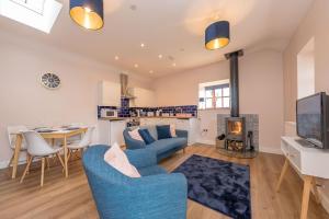 a living room with a blue couch and a tv at Bwthyn-Cerrig in Llanerchymedd