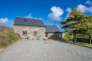 a stone house with a gravel driveway in front of it at Bwthyn-Cerrig in Llanerchymedd