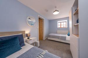 a small bedroom with a bed and a mirror at Bwthyn-Cerrig in Llanerchymedd