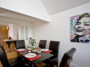 a dining room table with chairs and a painting on the wall at Bredon Court, Poseidon Penthouse in Newquay
