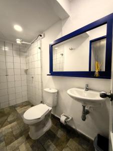 een badkamer met een toilet, een wastafel en een spiegel bij Hotel Colonial San Roque in San Roque