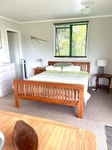 een slaapkamer met een houten bed en een raam bij First Light in Mangawhai