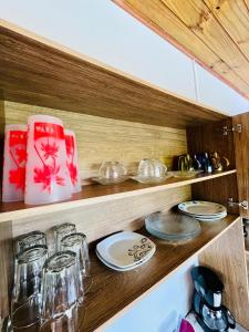 Eine Küche mit Tellern und Gläsern auf einem Holzregal in der Unterkunft Acomodação tranquila confortável 15 MT da praia in Florianópolis