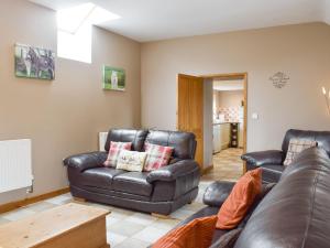 Penbrynにあるザ グラナリーの革張りのソファとテーブルのあるリビングルーム