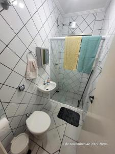 ein weißes Badezimmer mit Toilette und Waschbecken in der Unterkunft Casa em Caraguá, uma quadra da praia com ar in Caraguatatuba + 84 Fotos
