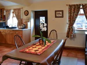 a dining room table with a flower on top of it at Swallows Nest-18094 in Cloughton