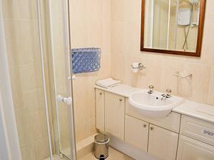 a white bathroom with a shower and a sink at Blue Waves in Perranporth