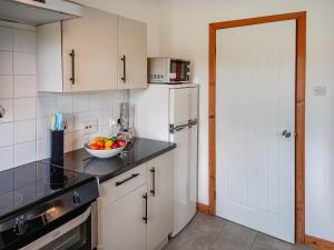 a kitchen with white cabinets and a bowl of fruit on the counter at Birch Lodge - 28880 in Torcastle