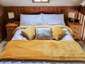 a bed with white sheets and pillows on it at Elm Barn Lodge in Freethorpe