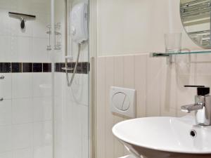 a white bathroom with a sink and a shower at Yew Tree Bothy in Old Brampton +2 photos