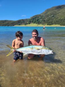 Un hombre y un niño en el agua con un pez. en Paradise HQ Pukenui, en Pukenui 12 fotos más