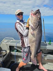 un hombre de pie en un barco sosteniendo un pez grande en Paradise HQ Pukenui, en Pukenui