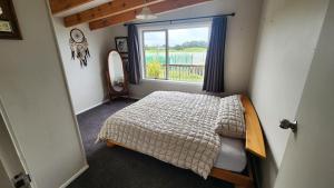 Un dormitorio pequeño con una cama y una ventana. en Paradise HQ Pukenui, en Pukenui