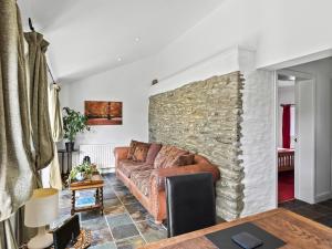 a living room with a couch and a stone wall at Kite Cottage in Capel-Ifan