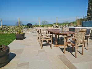 a wooden table and chairs on a patio at Eithinog Ganol in Llandwrog