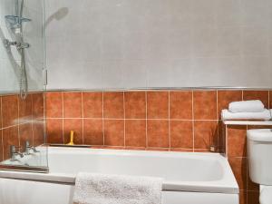 a bathroom with a bath tub and a toilet at Boundary Gallery Cottage in Framlingham +1 photo