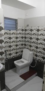 a bathroom with a toilet in front of a wall at ISKCON Mayapur Apartments - Daily & Monthly Rentals- PRIME LOCATION - SERVICED Apartment, 5 MIN to MAIN ISKCON TEMPLE in mayapur