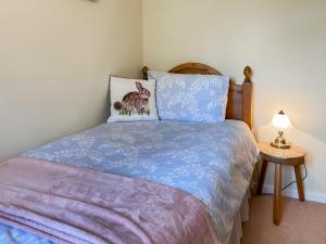 a bedroom with a bed with a blue comforter at Pipit Cottage in Burnsall