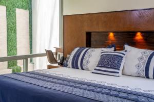 a bedroom with a bed with blue and white pillows at Galerias Oaxaca Suites in Oaxaca City +71 photos