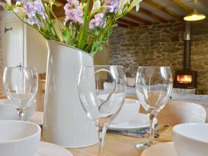 eine Vase mit Blumen auf einem Tisch mit Brille in der Unterkunft Ivy Bush Cottage in Llanddewi-Brefi