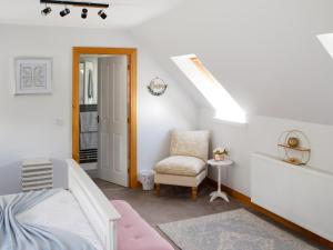 ein weißes Schlafzimmer mit einem Bett und einem Stuhl in der Unterkunft Rose Cottage in Dingwall