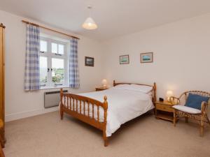 ein Schlafzimmer mit einem Bett, einem Fenster und einem Stuhl in der Unterkunft Berrystead Upper Flat in Salcombe