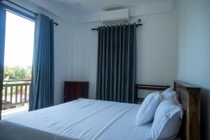 a bedroom with a bed and a large window at Bailey Beach Villa in Ahangama