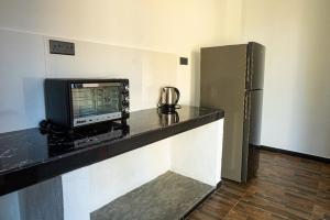 a kitchen with a counter with a tv and a refrigerator at Bailey Beach Villa in Ahangama