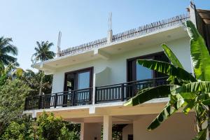 a house with a balcony and palm trees at Bailey Beach Villa in Ahangama +11 photos