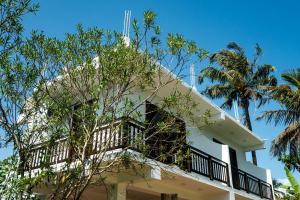 a white building with a balcony and palm trees at Bailey Beach Villa in Ahangama