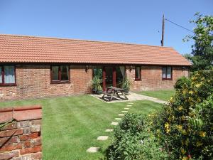 Una casa de ladrillo con una mesa de picnic en el patio. en Meadow View, en Leiston 7 fotos más