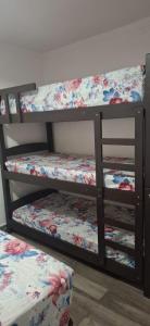 ein Dreifach-Etagenbett mit geblümter Bettwäsche und einem Kissen in der Unterkunft Casa na praia mongagua próximo da plataforma in Mongaguá