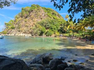 a beach with people swimming in the water at Coucher de soleil in Bouillante